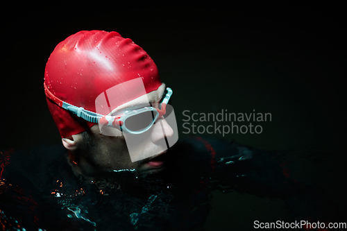 Image of Authentic triathlete swimmer having a break during hard training on night neon gel light