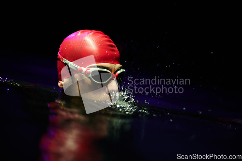 Image of A determined professional triathlete undergoes rigorous night time training in cold waters, showcasing dedication and resilience in preparation for an upcoming triathlon swim competition