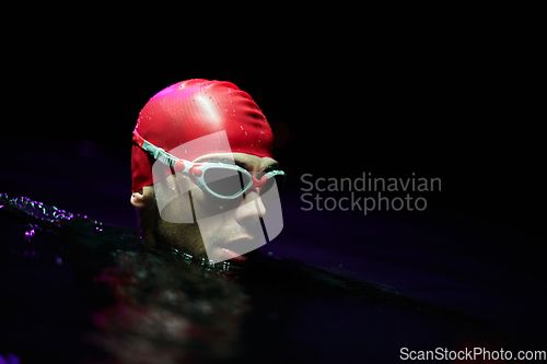 Image of A determined professional triathlete undergoes rigorous night time training in cold waters, showcasing dedication and resilience in preparation for an upcoming triathlon swim competition