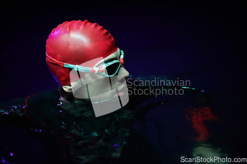 Image of Authentic triathlete swimmer having a break during hard training on night neon gel light