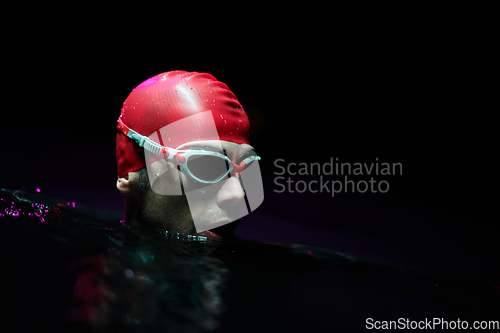 Image of A determined professional triathlete undergoes rigorous night time training in cold waters, showcasing dedication and resilience in preparation for an upcoming triathlon swim competition