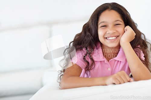 Image of Smile, sweet and portrait of girl child at her home with positive, good and confident attitude. Happy, cute and face of young kid from Colombia sitting and relaxing in living room at modern house.