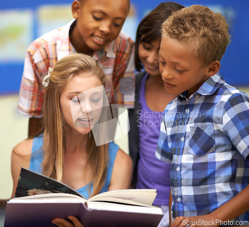 Image of Children, reading book and classroom education for teaching, learning and support in language development. Happy kids with mentor or girl in leadership helping students with education or storytelling