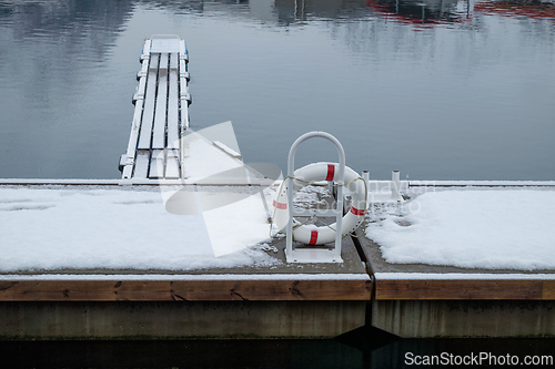 Image of Snow-Covered Dock With Lifebuoy and Wooden Pier on a Serene Wint