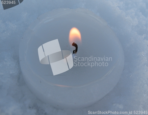 Image of white lit candle in snowflakes