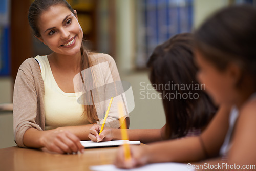 Image of Happy teacher, students and writing in class for education, learning or tutoring at school. Woman, mentor or educator smile for helping kids or children with books in study, library or classroom