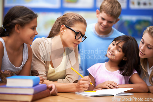 Image of Teacher, students and writing for learning, education or tutoring in classroom at school. Woman, mentor or educator helping young kids or children with books for studying on literature in class