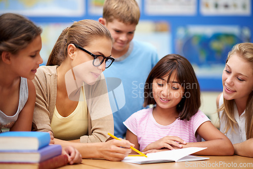 Image of Happy teacher, students and writing for education, learning or tutoring in classroom at school. Woman, mentor or educator helping young kids or children with books for studying or literature in class