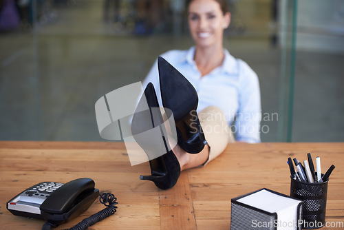 Image of Woman, feet and relax on table in office with smile, pride or done with goal, relief or portrait at finance agency. Person, employee and happy with shoes on desk, finished or achievement in workplace