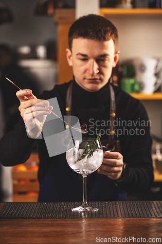 Image of Bartender is adding ingredient in glass