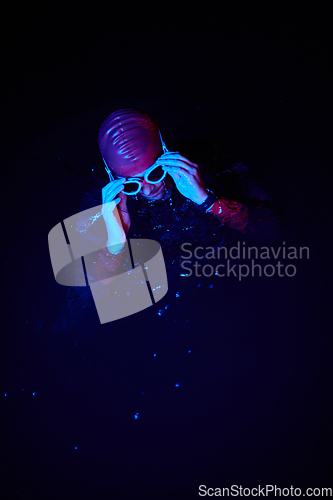 Image of Authentic triathlete swimmer having a break during hard training on night neon gel light