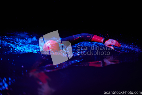 Image of Authentic triathlete swimmer having a break during hard training on night neon gel light