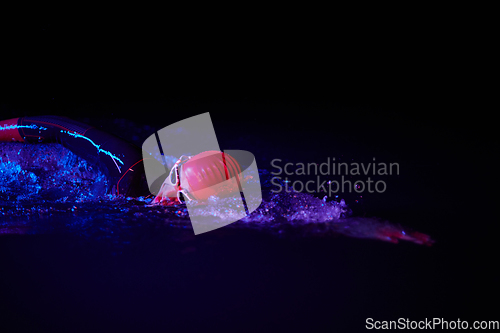 Image of Authentic triathlete swimmer having a break during hard training on night neon gel light