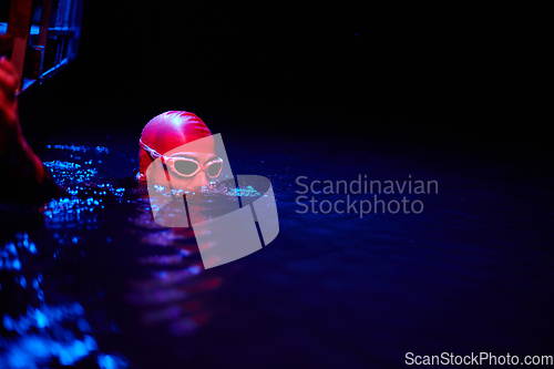 Image of Authentic triathlete swimmer having a break during hard training on night neon gel light