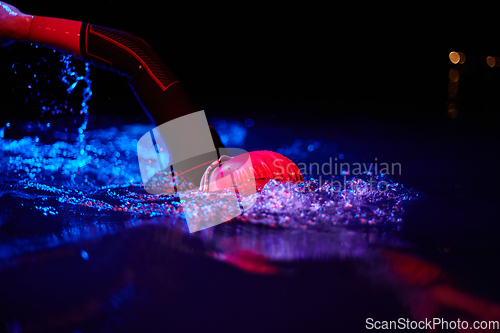 Image of Authentic triathlete swimmer having a break during hard training on night neon gel light