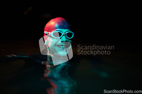 Image of Authentic triathlete swimmer having a break during hard training on night neon gel light