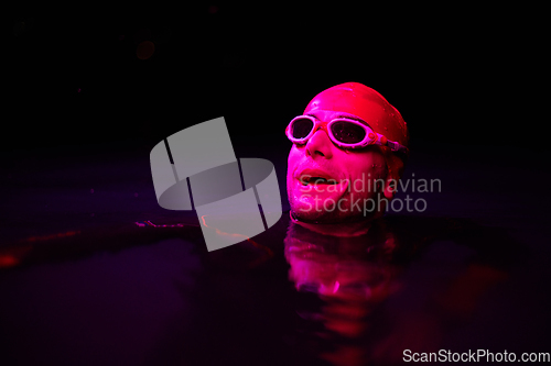 Image of Authentic triathlete swimmer having a break during hard training on night neon gel light