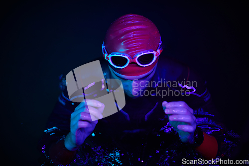 Image of authentic triathlete swimmer having a break during hard training on night neon gel light