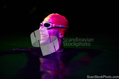 Image of Authentic triathlete swimmer having a break during hard training on night neon gel light