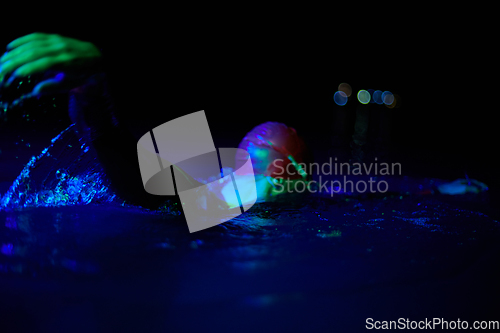 Image of Authentic triathlete swimmer having a break during hard training on night neon gel light