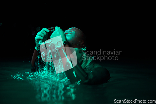 Image of Authentic triathlete swimmer having a break during hard training on night neon gel light