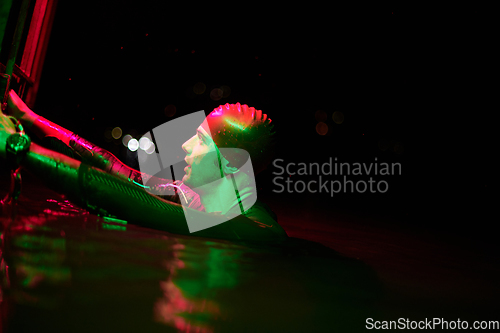 Image of authentic triathlete swimmer having a break during hard training on night neon gel light