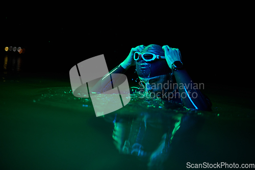 Image of Authentic triathlete swimmer having a break during hard training on night neon gel light