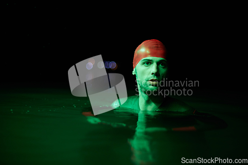 Image of Authentic triathlete swimmer having a break during hard training on night neon gel light
