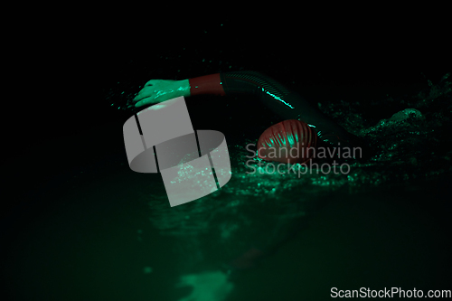 Image of Authentic triathlete swimmer having a break during hard training on night neon gel light