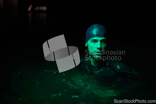 Image of Authentic triathlete swimmer having a break during hard training on night neon gel light