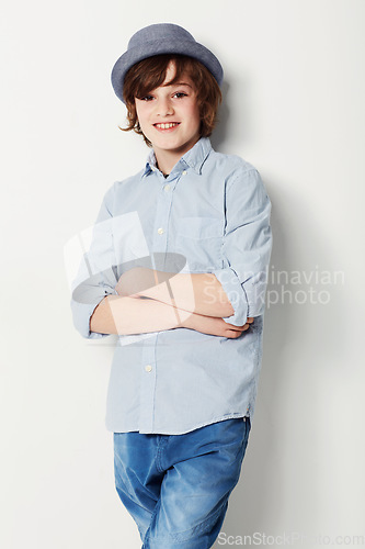 Image of Boy, confidence and portrait for fashion in studio, cool clothing and arms crossed by white background. Happy male person, child and cool hat by backdrop or pride for style, face and trendy outfit