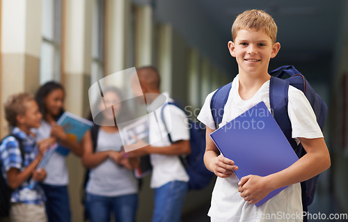 Image of Boy, portrait and smile in corridor of school with backpack and books for learning, education or knowledge. Student, person and face with happy in building or hallway before class or ready to study