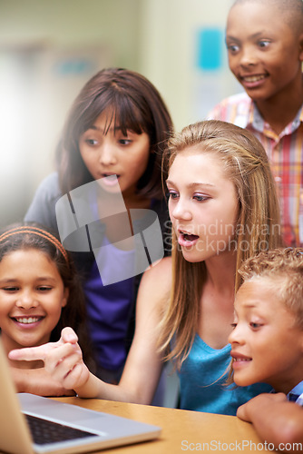 Image of Young tutor, laptop and teaching kids, children or pupils technology, social media or research in class. Group of elementary students with mentor showing tech, internet or online search in classroom