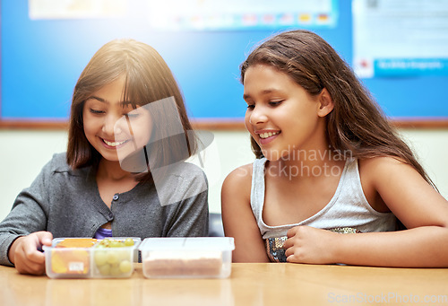 Image of Happy girls, students and lunchbox of food in classroom at school for meal, break or snack time together. Young little kids or elementary children smile with container for fruit and sandwich in class