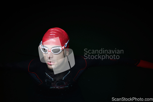 Image of A determined professional triathlete undergoes rigorous night time training in cold waters, showcasing dedication and resilience in preparation for an upcoming triathlon swim competition