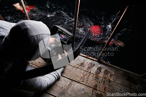 Image of Videographer taking action shot of triathlon swimming athlete at night