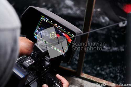 Image of Videographer taking action shot of triathlon swimming athlete at night