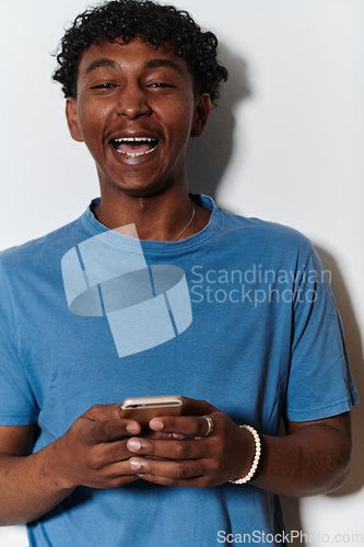 Image of African American teenager engages with his smartphone against a pristine white background, encapsulating the essence of contemporary digital connectivity and youth culture