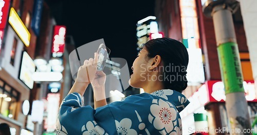 Image of Woman, phone photography and buildings in night, city or street for architecture, vacation and web blog. Japanese, person and happy for holiday, smartphone or journey with social media in Tokyo