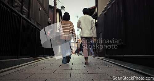 Image of Women, walking and back by city street and travel for bonding in urban town in winter. Friends, wellness and commute together in neighborhood for social trip, vacation and outdoor in tokyo on journey