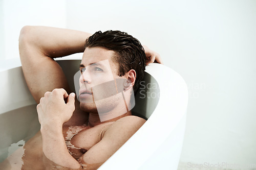 Image of Man, bath and thinking for relax in bathroom with hands, wellness and contemplating in the morning. Model, person and lying down in bath for self care, grooming and cosmetic routine with shirtless