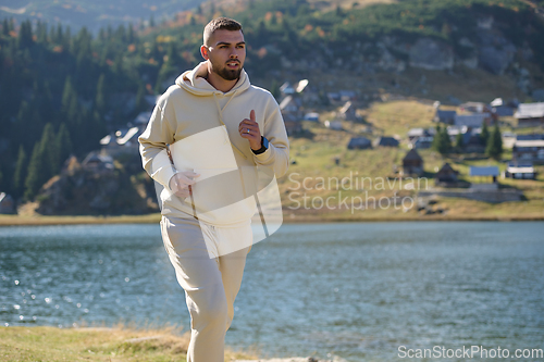 Image of Athletic man maintains his healthy lifestyle by running through the scenic mountain and lakeside environment, showcasing a commitment to fitness and well-being