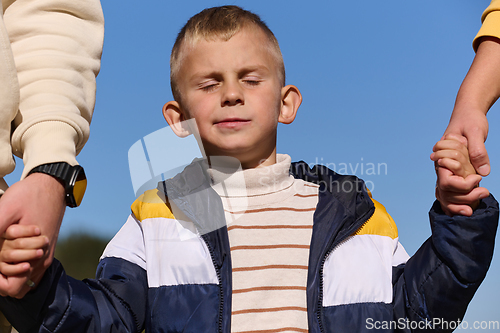 Image of A close-up shot features a young boy walking hand in hand with his parents , as they joyfully explore the wonders of nature together, creating lasting memories of familial love and outdoor adventure