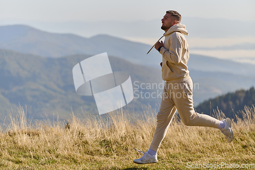 Image of A handsome man maintains his healthy lifestyle as he runs along beautiful natural trails, embodying the essence of fitness, wellness, and vitality in the midst of scenic outdoor surroundings.