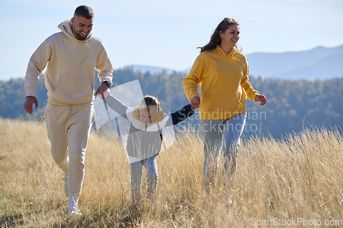 Image of A modern family, along with their son, revels in the joy of a muddy day in nature, running and playing together, encapsulating the beauty of a healthy and active lifestyle