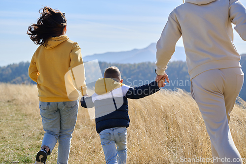 Image of A modern family, along with their son, revels in the joy of a muddy day in nature, running and playing together, encapsulating the beauty of a healthy and active lifestyle