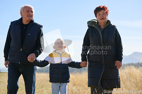 Image of Elderly couple enjoys a leisurely stroll in nature with their grandchild, creating precious moments of intergenerational bonding amidst the serene and picturesque surroundings