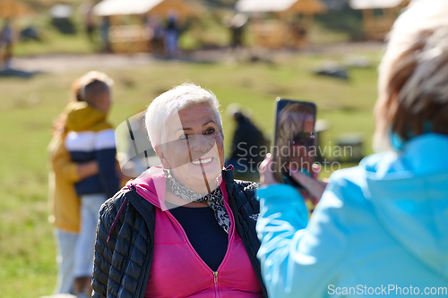 Image of An elderly pair of women captures a timeless moment on their smartphones, blending technology with the serene beauty that surrounds them