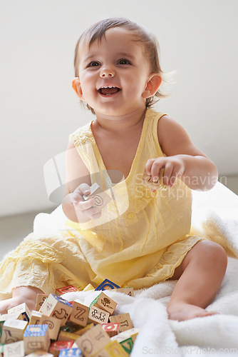 Image of Baby, girl and happy, blocks as toys for learning, playing at home for education and alphabet. Growth, early childhood development and young kid with educational activity, playtime and montessori