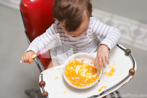 Image of Baby eating, high chair and food, nutrition and health for childhood development and wellness. Healthy, growth and toddler person at home, vegetable or fruit, hungry kid with lunch or dinner meal